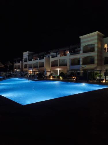 a large swimming pool in front of a building at night at Apartment in Port Ghalib Marina City in Port Ghalib