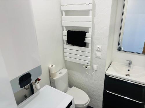 une salle de bain blanche avec des toilettes et un lavabo dans l'établissement L'instant Malfato, Duplex avec vue sur les bateaux, au Cap d'Agde