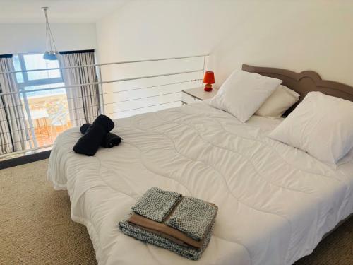 - un grand lit blanc avec 2 serviettes dans l'établissement L'instant Malfato, Duplex avec vue sur les bateaux, au Cap d'Agde