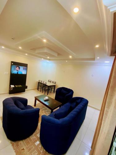 a living room with blue couches and a tv at Hona Al Holm Furnished Units in Dammam