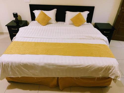a large bed with yellow and white sheets and pillows at Hona Al Holm Furnished Units in Dammam