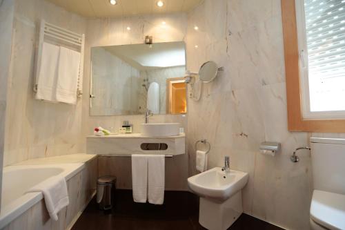 a white bathroom with a tub and a sink at Hotel Spa Congreso in Teo