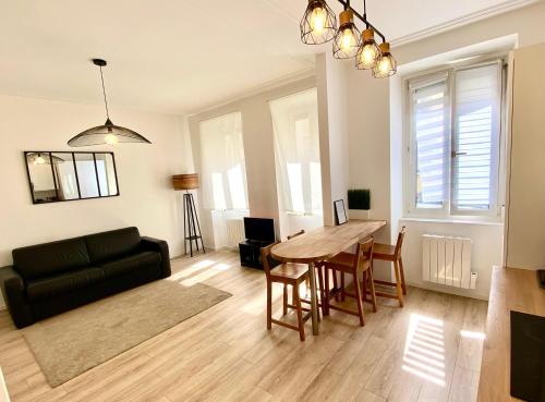een woonkamer met een tafel en een zwarte bank bij Cosy Appartement 48m Strasbourg Centre et Gare à Pied Proche Musée d Art Moderne Wifi 4 Personnes in Straatsburg