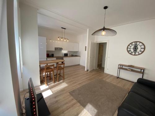 een woonkamer en een keuken met een tafel en een klok bij Cosy Appartement 48m Strasbourg Centre et Gare à Pied Proche Musée d Art Moderne Wifi 4 Personnes in Straatsburg
