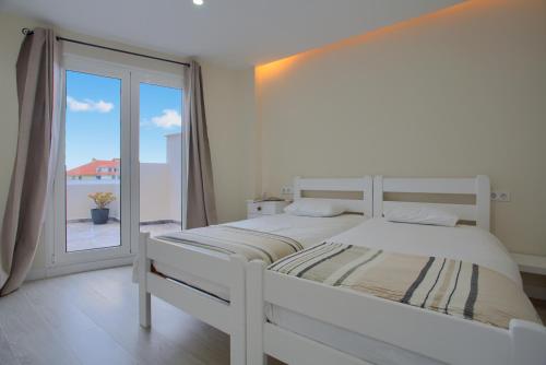 a white bedroom with a large bed and a window at Mojo Surf Yoga House in La Orotava