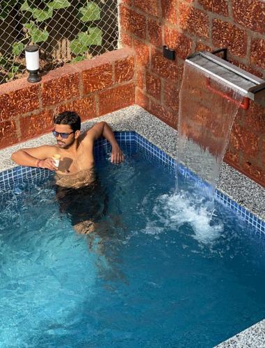a man in a swimming pool with a fountain at Zuluk Luxury Pool Villa with Swimming Pool in Ratnagiri