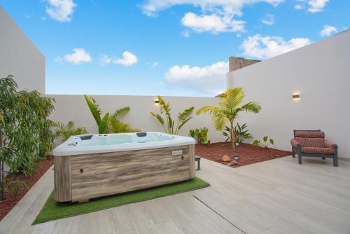 a jacuzzi tub in a patio with a chair at Mojo Surf Yoga House in La Orotava