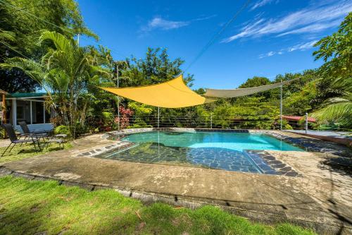 a yellow umbrella over a swimming pool in a yard at Bamboo River House and Hotel in Dominical