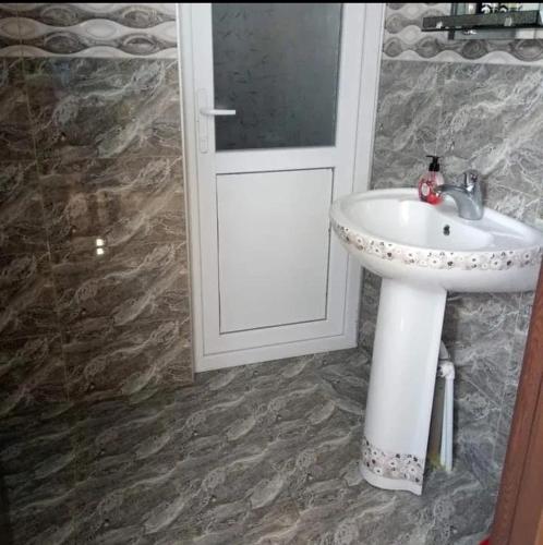 a bathroom with a white sink and a door at Guesthouse Amiran Tabatskuri in Tabatsquri