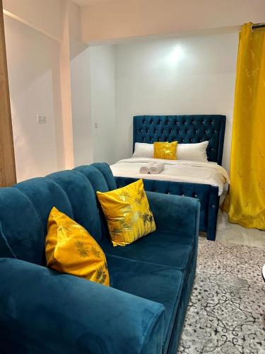 a blue couch with yellow pillows next to a bed at Gee Kamakis Airbnbs in Ruiru