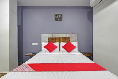 a bedroom with a bed with red pillows at Hotel O Sri Sai Regency in Hyderabad