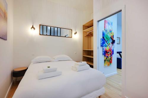 - une chambre avec un lit blanc et un ordinateur portable dans l'établissement Appartement cosy à deux pas de République, à Paris