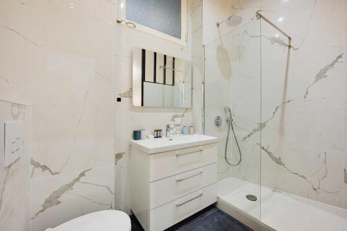 une salle de bain blanche avec un lavabo et une douche dans l'établissement Appartement cosy à deux pas de République, à Paris