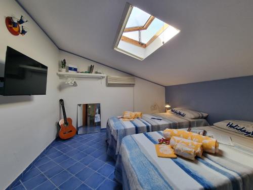 a room with two beds and a television and a guitar at Respiro di Mare by Holiday World in Buonfornello