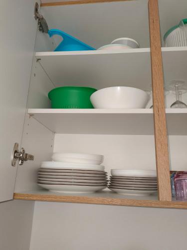 une étagère avec des assiettes et des bols dans une cuisine dans l'établissement Petit appartement, à Lourdes