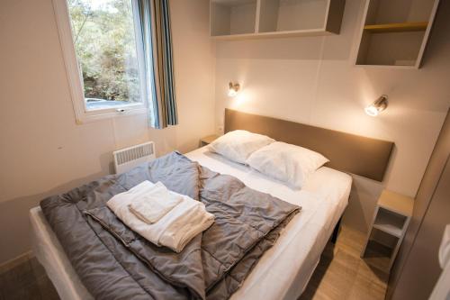 une chambre avec un lit avec deux oreillers dessus dans l'établissement Camping les Chelles, à Olliergues