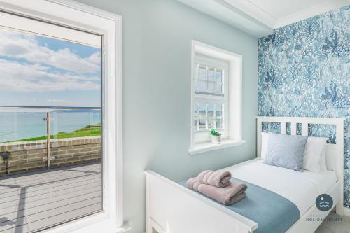 a bedroom with a window with a view of the ocean at Comfort Hill - Luxury hot tub sea views in Overcombe