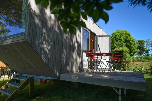 a tiny house with chairs on a deck at Tiny House Pioneer 1 - Salemer See in Salem