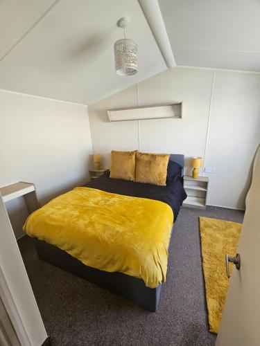 a bedroom with a large bed with a yellow blanket at AD static Towyn in Kinmel Bay