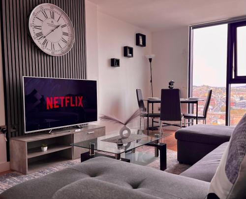 a living room with a television and a clock on the wall at Penthouse Gem, Central, Scenic Views, Stylish, Modern, City Centre 2BR in Sheffield