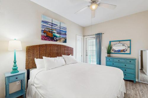 a bedroom with a white bed and a blue dresser at Tiki House in Corpus Christi