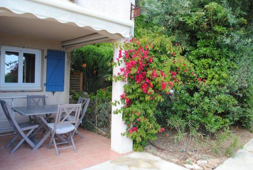 - une table et des chaises sur une terrasse couverte avec des fleurs rouges dans l'établissement appartement vacances Les Issambres, à Roquebrune-sur Argens