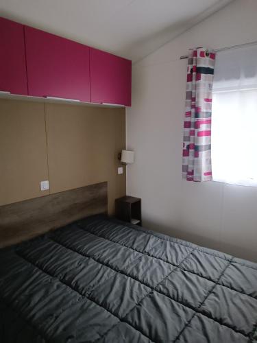 une chambre avec un lit avec des armoires violettes et une fenêtre dans l'établissement mobilhome à la mer, à Montreuil-sur-Ille