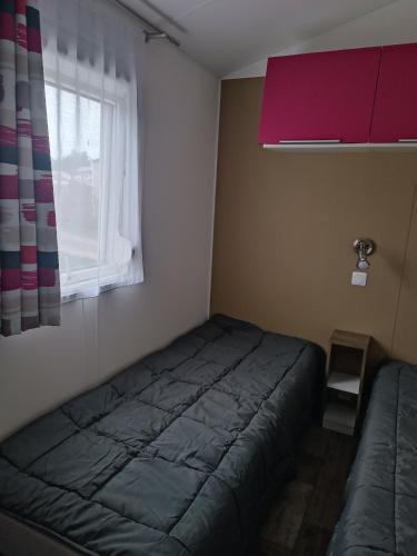 une chambre avec un lit et une fenêtre dans l'établissement mobilhome à la mer, à Montreuil-sur-Ille
