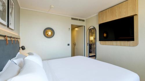 a bedroom with a white bed and a flat screen tv at Campanile PRIME - Nice Airport in Nice
