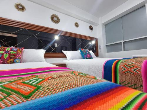 a bedroom with two beds with colorful blankets at Hotel Hatun Sumac Wasi in Sicuani