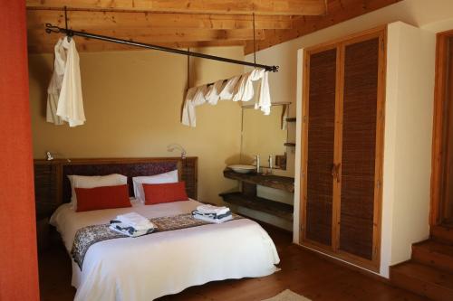a bedroom with a bed with white sheets and red pillows at Monte D´Sancho in Aljezur