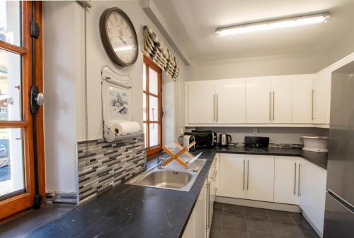 une cuisine avec un évier et une horloge murale dans l'établissement Chalet Christiania, à Saint-Jean-dʼAulps