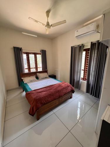 a bedroom with a bed and two windows at Sree Shivanya Homes in Trivandrum