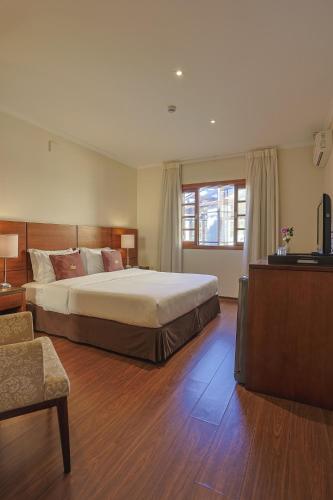 a large bedroom with a large bed and a television at Hotel Le Renard - Campos do Jordao in Campos do Jordão