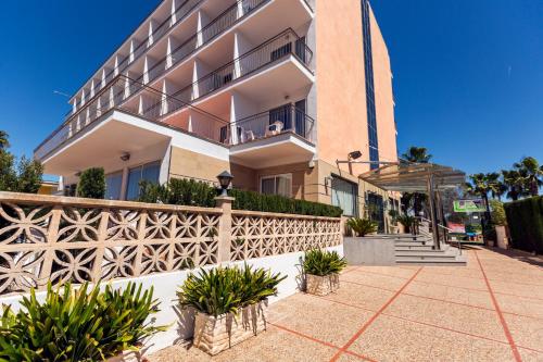 a building with a fence and plants in front of it at Hotel Don Miguel Playa in Playa de Palma