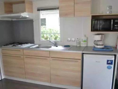 une cuisine avec un évier et une fenêtre dans l'établissement Camping - Piscine - eechfc, à Mézos