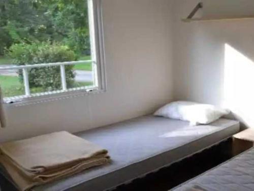 un lit assis dans une pièce avec une fenêtre dans l'établissement Camping - Piscine - eechfc, à Mézos