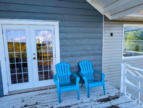 two blue chairs sitting on the front porch of a house at Cliff Haven on the Bay in Alert Bay