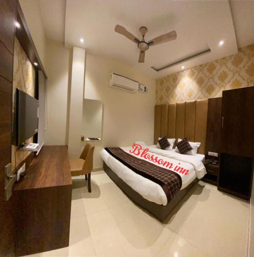 a bedroom with a bed and a flat screen tv at Hotel Blossom Inn in Amritsar