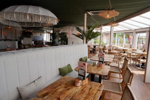 a dining room with wooden tables and chairs and tablesktop at Moderne chalet op het strand in Kropswolde