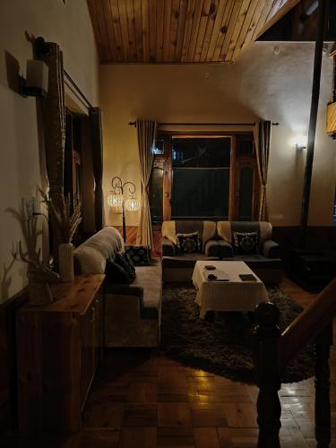 a living room with a couch and a table at The Dreamy Chalet in Nagar