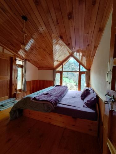 a bed in a wooden room with a window at The Dreamy Chalet in Nagar
