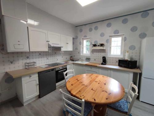 une cuisine avec une table en bois et des armoires blanches dans l'établissement NEW VILLA GLYCINES indépendante 2 chambres jardin clos bien situé, à Carcassonne
