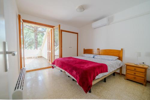 a bedroom with a bed with a red blanket at Villa in Tossa de Mar (Santa María de Llorell) in Tossa de Mar