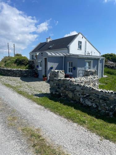 a white house with a stone wall next to a road at Calla Roundstone in Roundstone