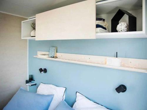 une chambre avec un mur bleu avec des étagères et des oreillers dans l'établissement Camping 3 étoiles - Parc aquatique - eehagb, à Châtelaillon-Plage