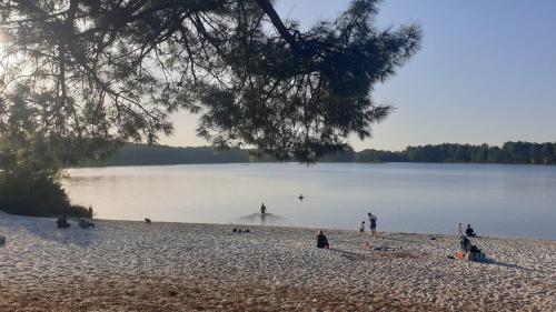 a group of people playing in the water on a beach at Le Gîte du Lac d'Hostens in Hostens