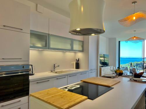 une cuisine avec des placards blancs et une grande fenêtre dans l'établissement Loft Centre-Ville Vue Mer, à Porto-Vecchio