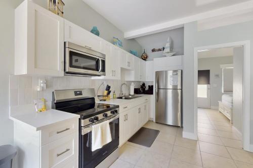 a kitchen with white cabinets and a stainless steel refrigerator at 53 Steps to Beach in Clearwater Beach