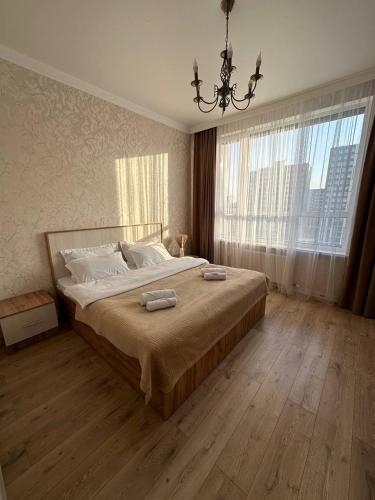 a bedroom with a large bed with a chandelier at Athletic city in Taldykolʼ